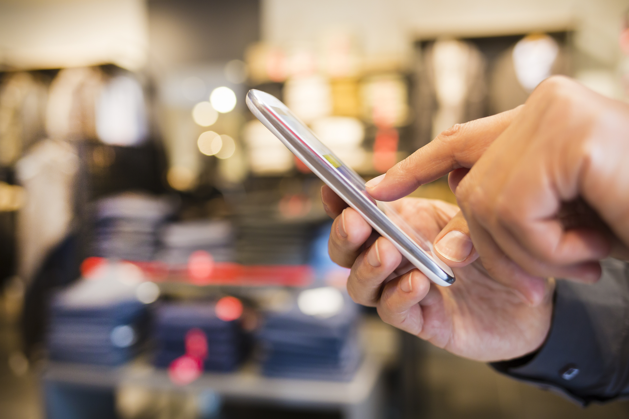 Close up of a man using mobile  phone in clothing store